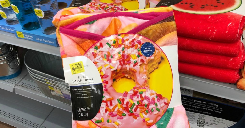 round beach towel shaped like a donut with sprinkles in front of store shelf
