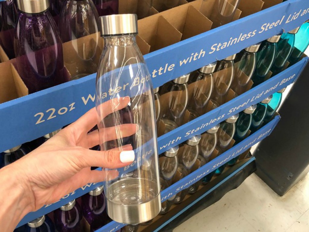 hand holding clear water bottle by store display