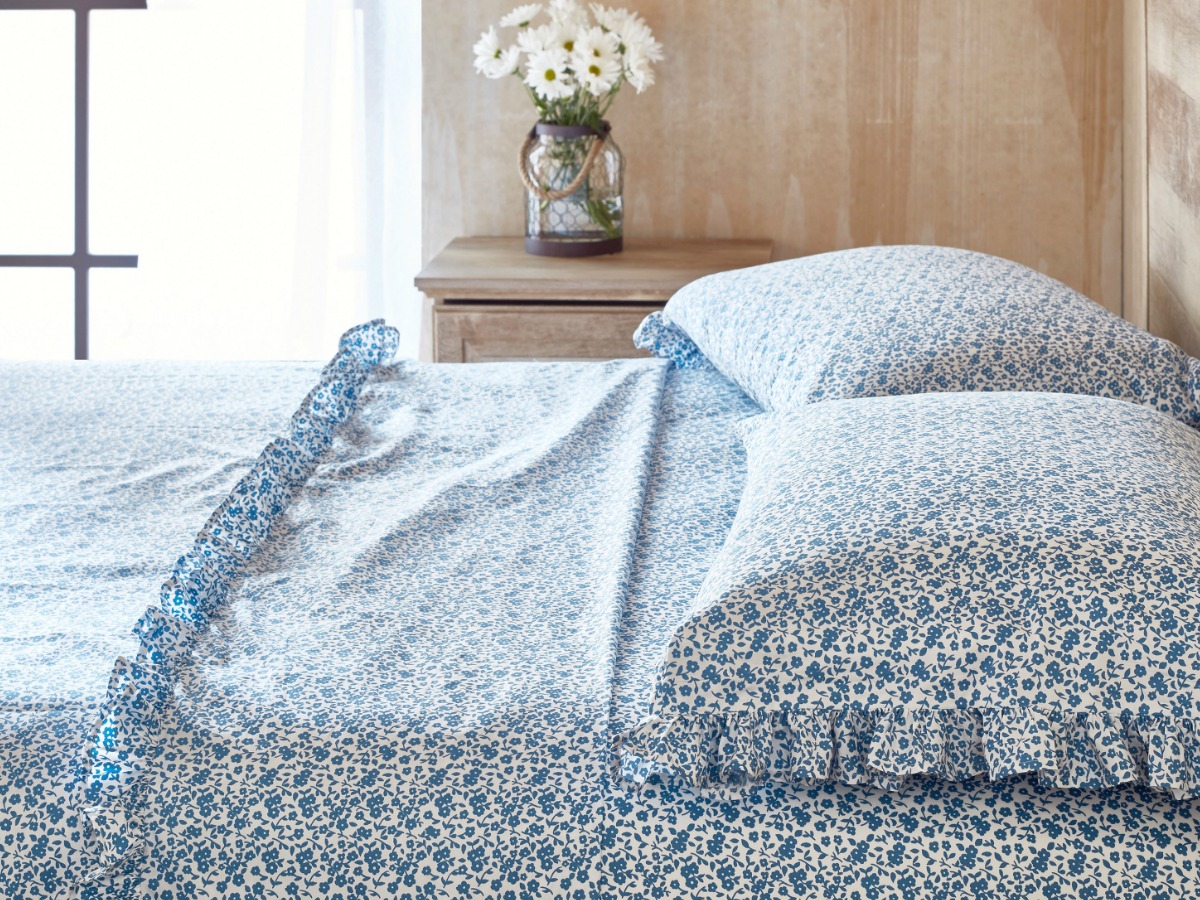 blue sheets on bed with flowers on table