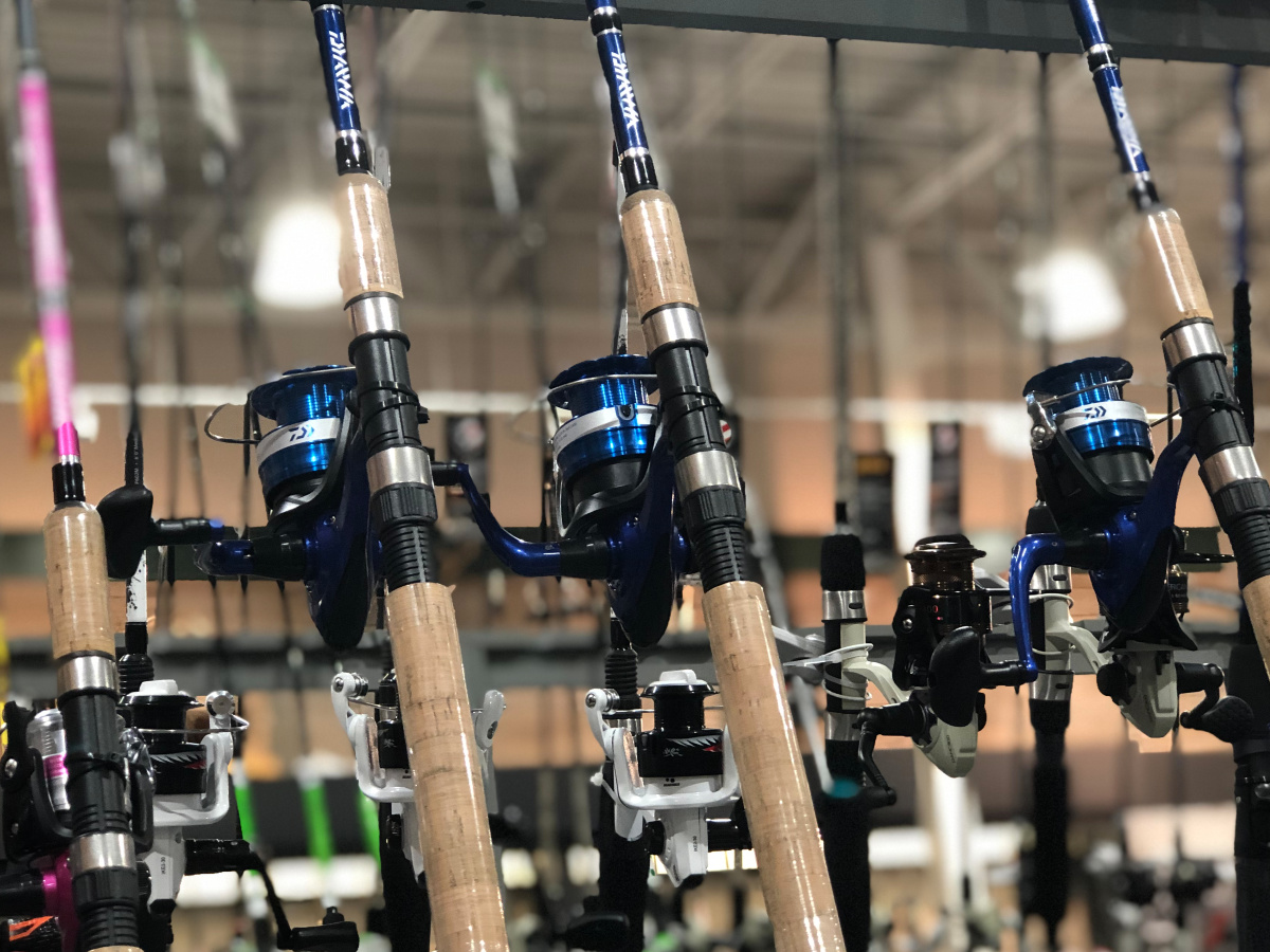 rows of blue spinning reels on fishing poles in a store