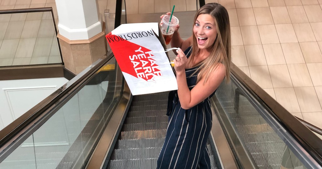 woman holding red white nordstrom shopping bag and starbucks drink