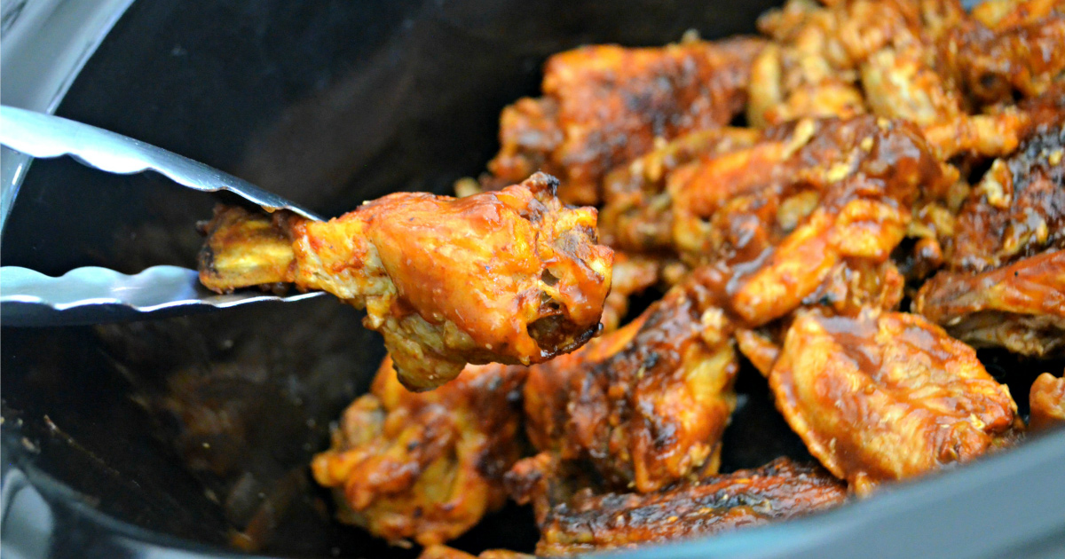 pulling out chicken wing from slow cooker - gameday food and football party food ideas