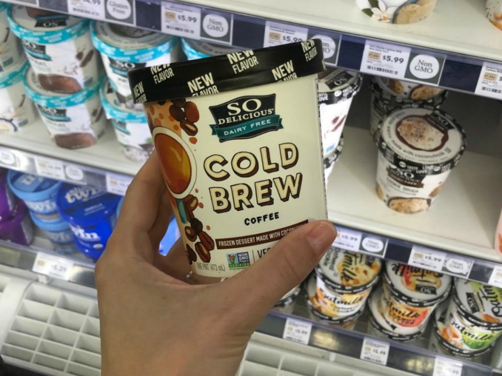 hand holding pint of ice cream by store freezer