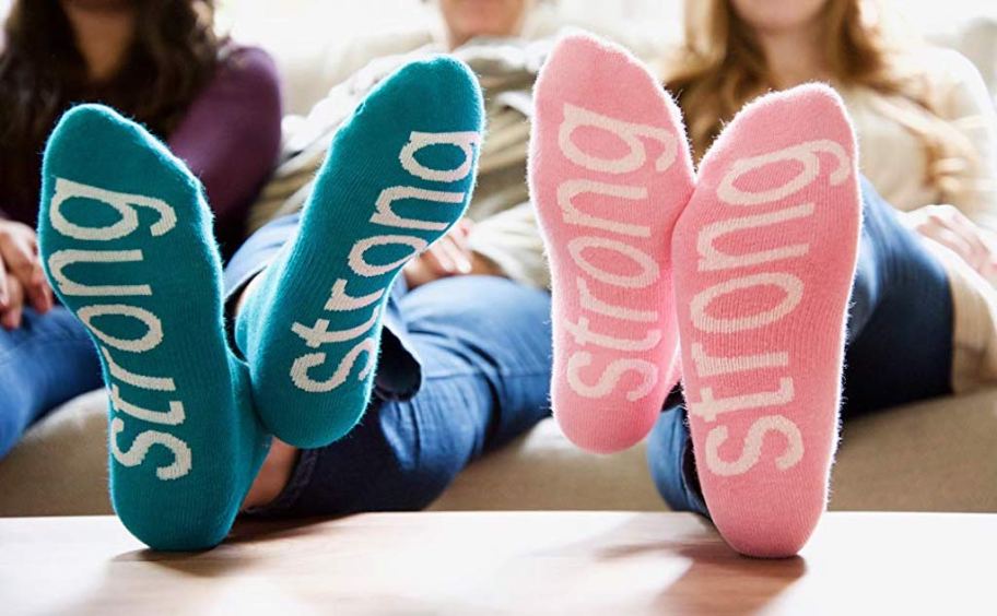 close up of blue and pink strong inspirational socks on bottom of peoples feet