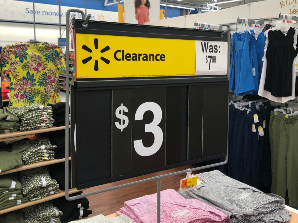 sign in store with $3 on it by tables of clothes