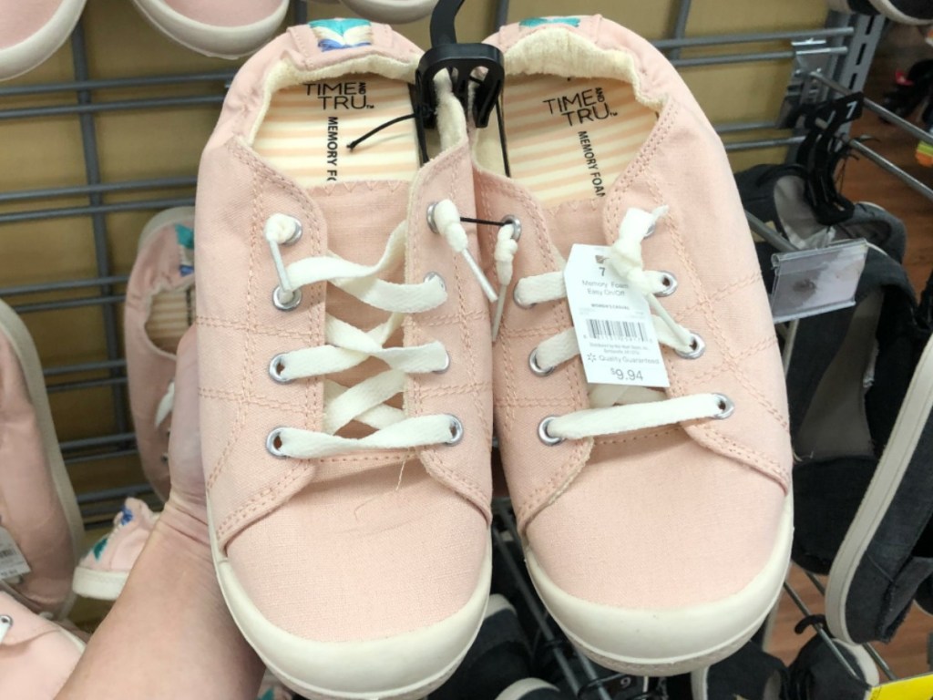 hand holding pink women's sneaker in a store
