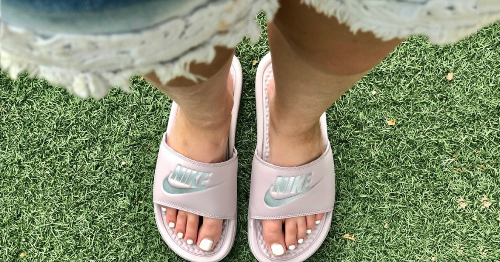 women's legs standing in grass with sandals on