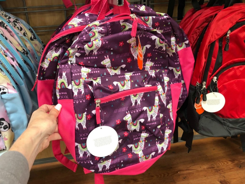 hand holding pink backpack with llamas on store display