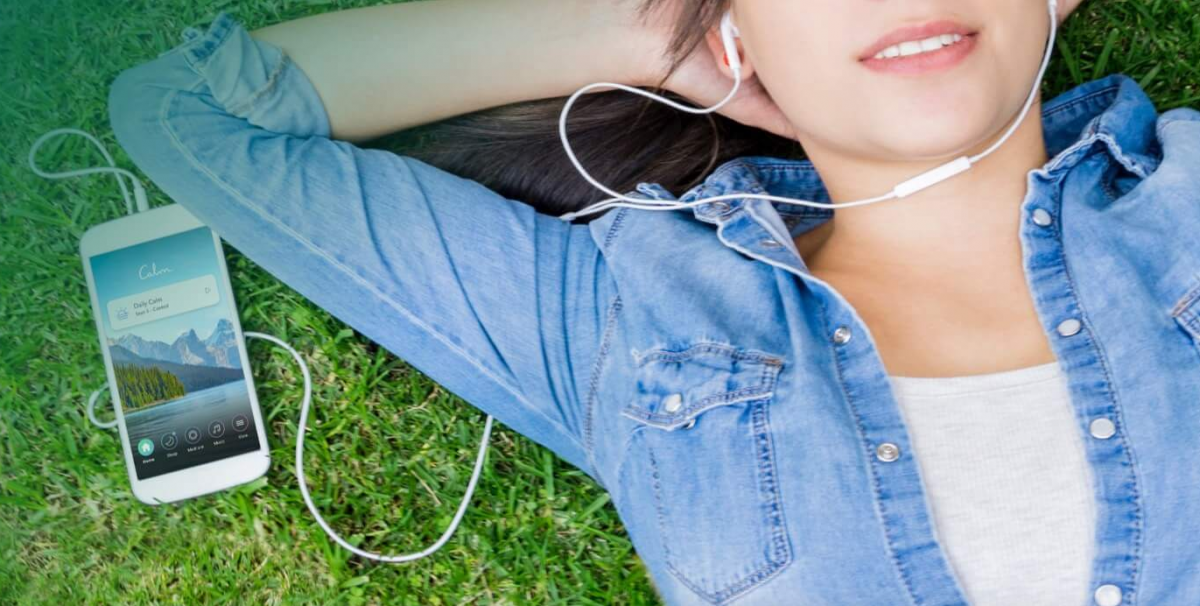 Woman listening to Calm App in grass