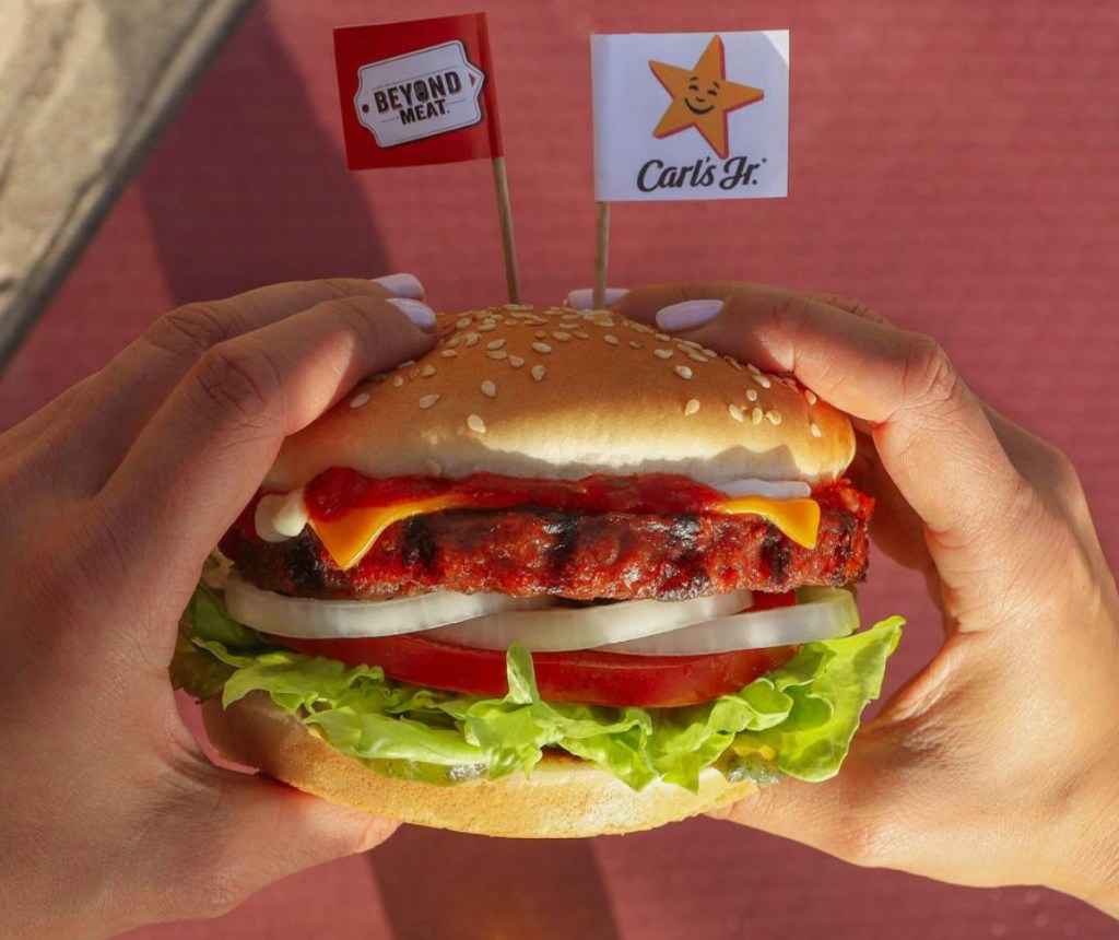 Hands holding a Beyond Meat plant-based burger from Carl's Jr.