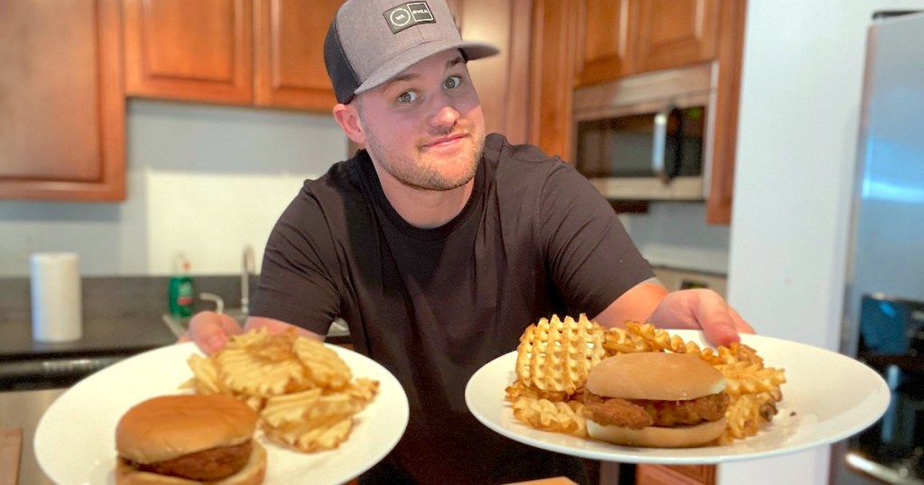 man holding chicken sandwiches and fries on two plates