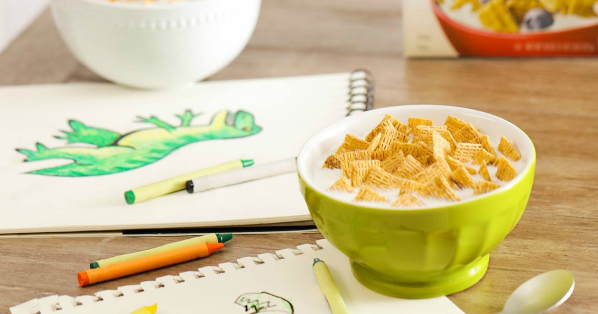 Life Cereal in a green bowl with milk near cereal box and drawing of a dinosaur