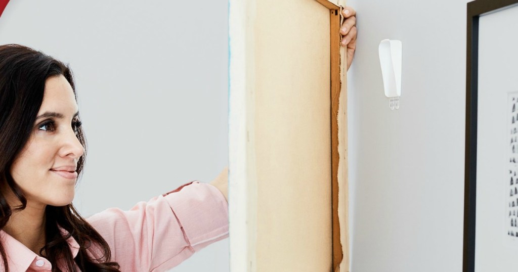 Woman hanging a canvas on the Command brand wall hanger