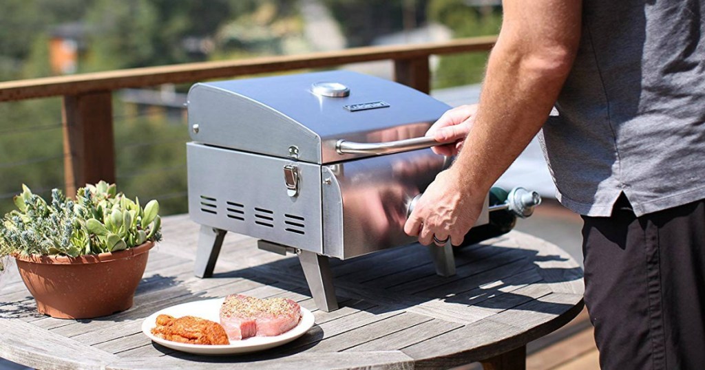 man opening a tabletop gas grill