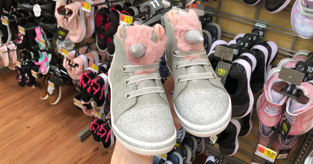 woman holding pair of girls unicorn shoes
