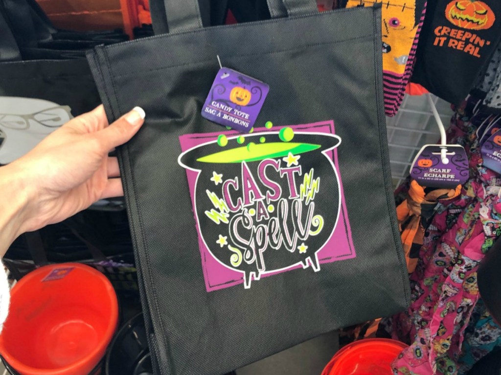 hand holding black tote bag in front of store display