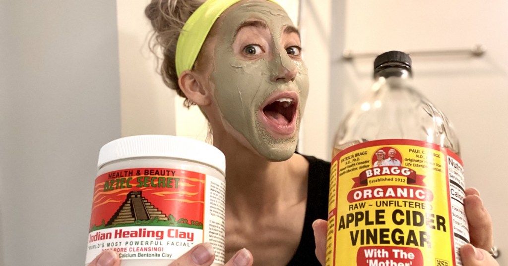 woman holding a jar of aztec healing clay and apple cider vinegar wearing green mask
