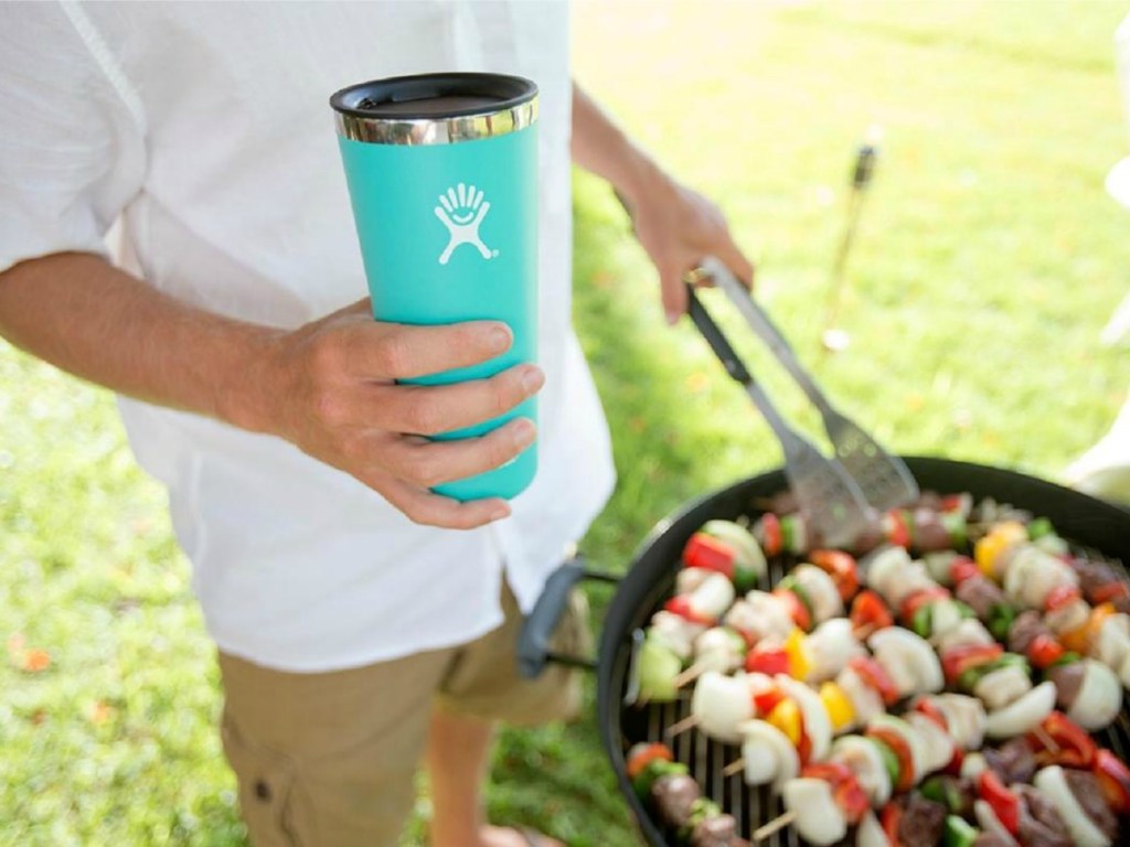man holding a hydro flask tumbler while grilling