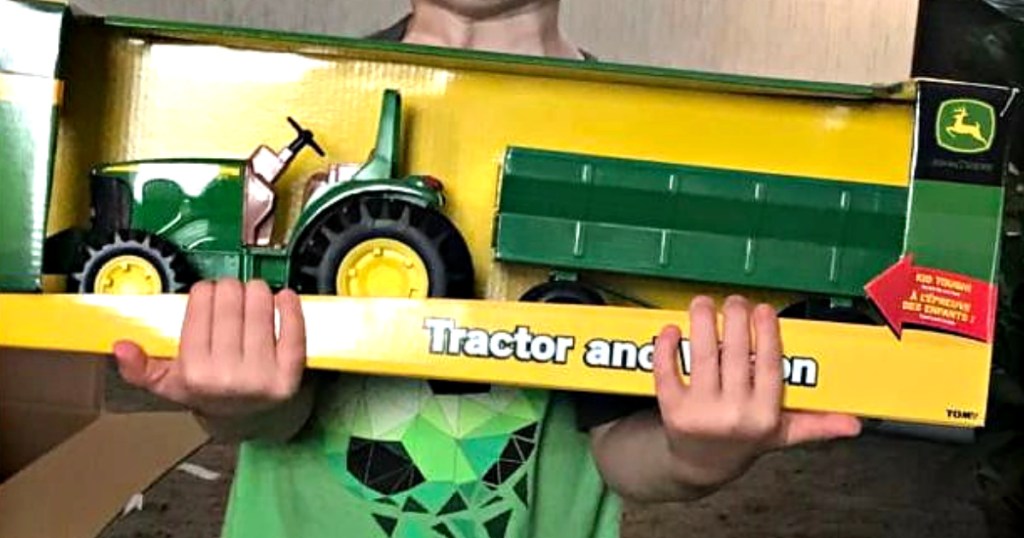 kid holding up john deer tractor toy