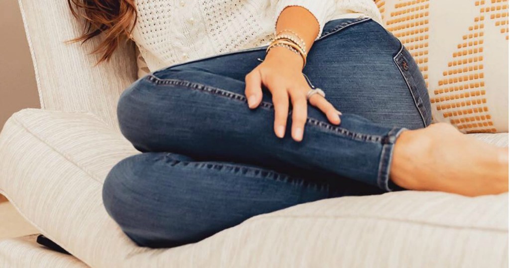 Woman wearing KUT From the Kloth Boyfriend Jeans while sitting on the sofa