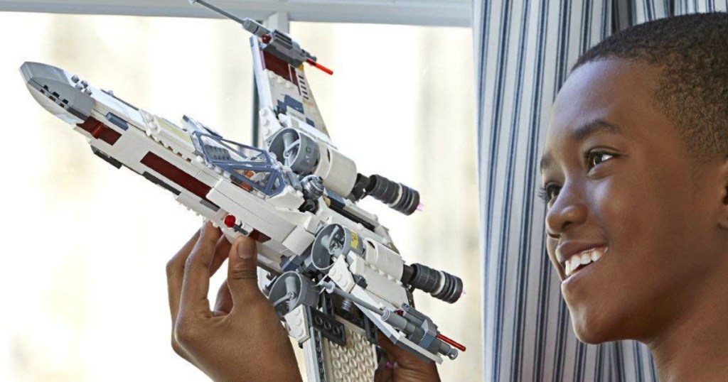 boy playing with a LEGO Star Wars X-Wing Starfighter