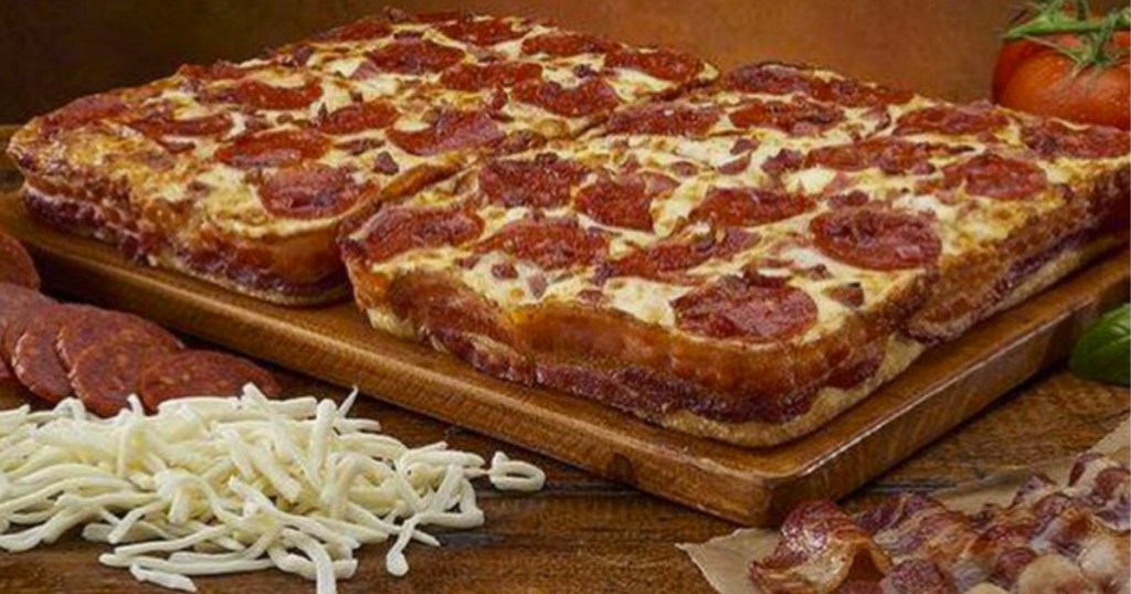 Pepperoni Pizza wrapped in bacon on platter with ingredients nearby