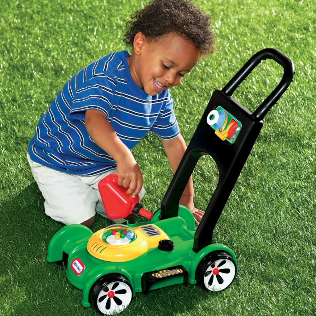 Little boy playing with a green and yellow toy mower from Little Tikes