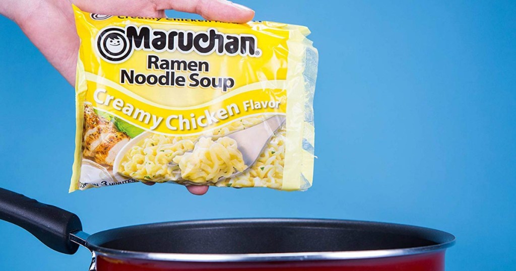 Creamy chicken flavored Ramen noodles in package in-hand over pan