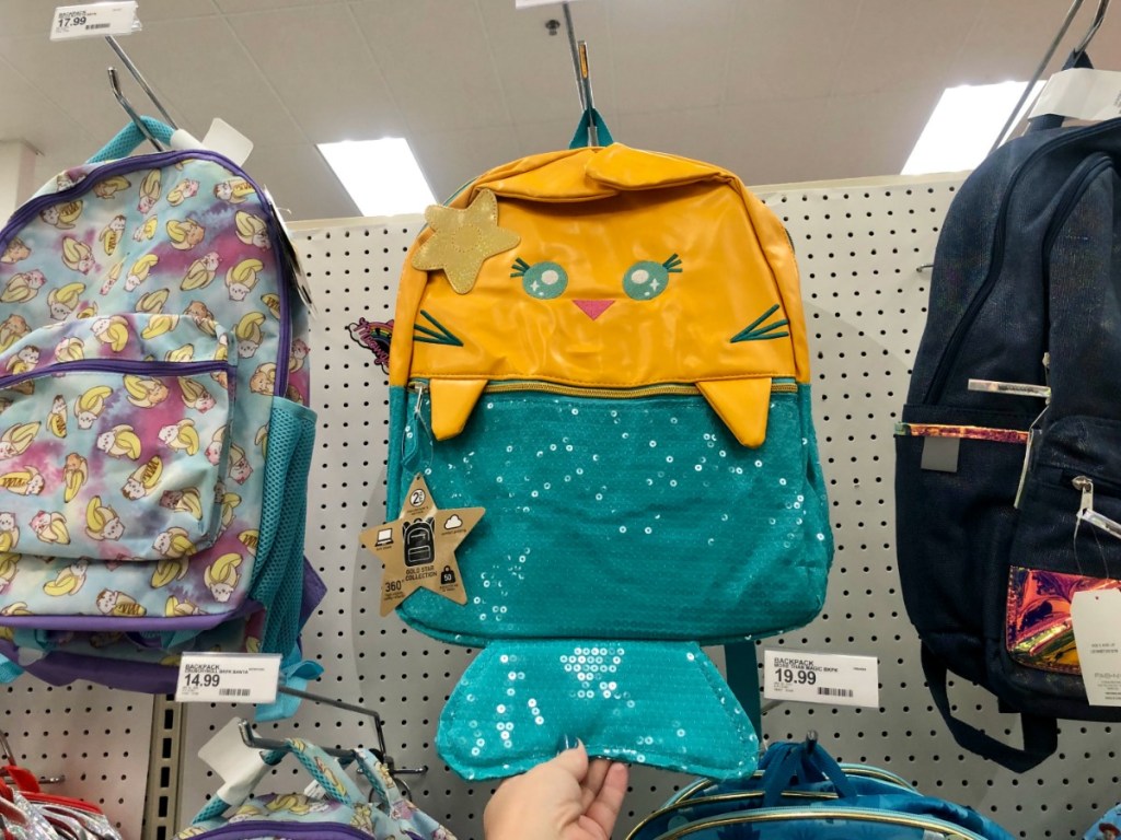 hand holding yellow and blue backpack