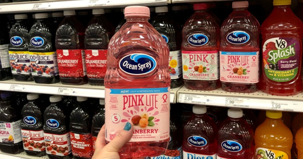 woman holding up Ocean Spray Pink Lite Cranberry Juice bottle in-store