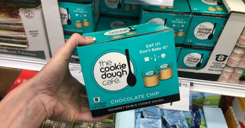 Hand holding box of edible chocolate chip cookie dough in Sam's Club store