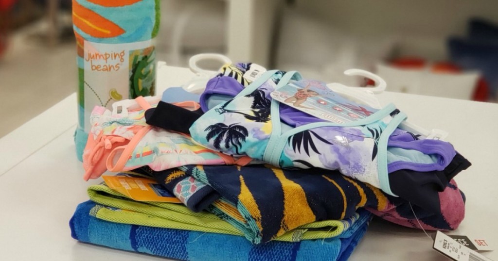 Kid's swimwear stacked near beach towels on counter at Kohl's