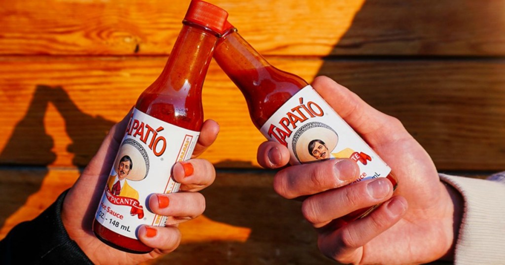 hands cheersing hot sauce bottles