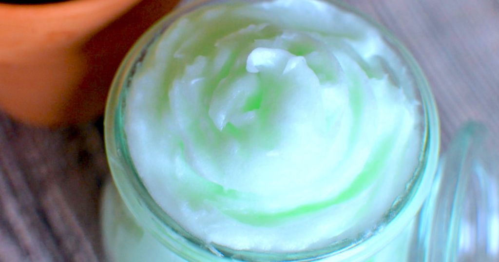glass jar filled with green whipped cooling coconut oil lotion