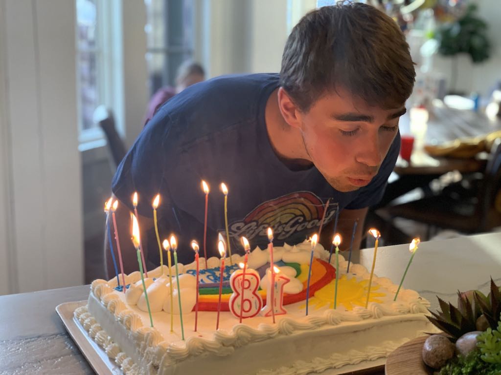 teenage boy blowing out candles on birthday cake 