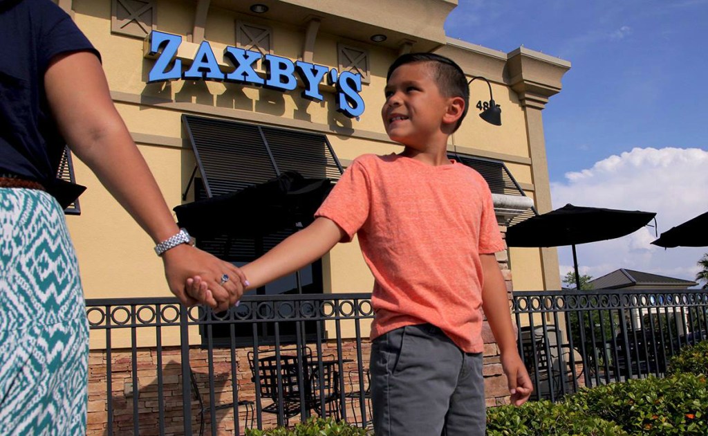 jongen en moeder houden elkaars hand vast bij Zaxby's's