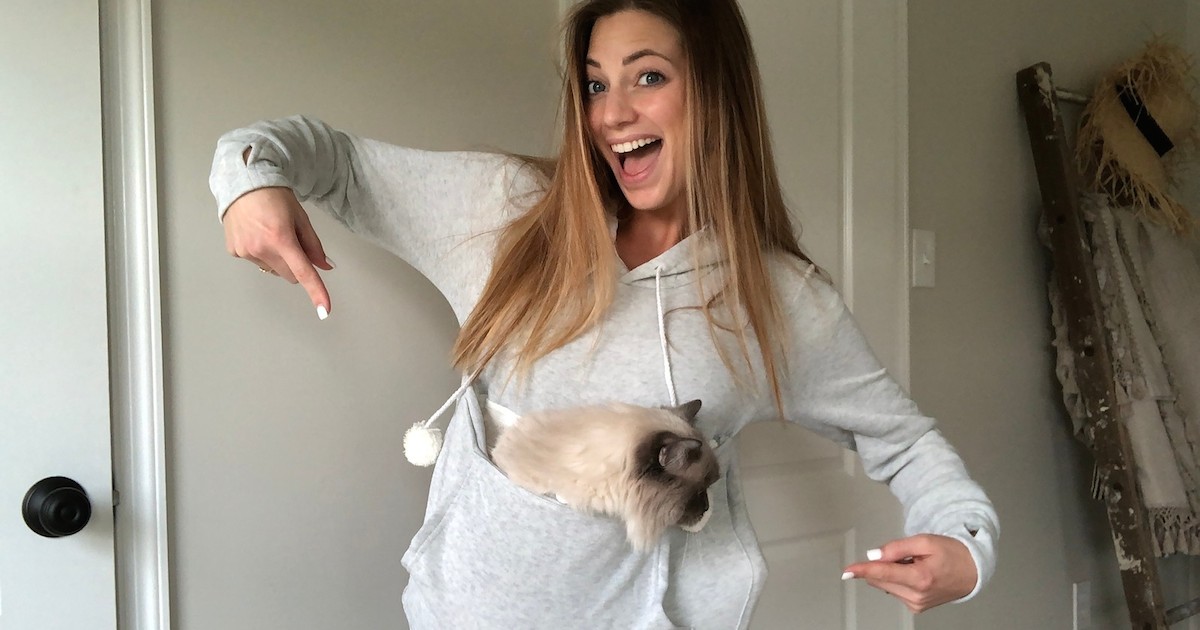 woman wearing light gray sweatshirt hoodie with cat inside