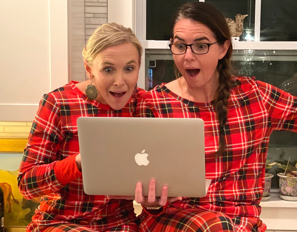 two woman staring at laptop in christmas jammies