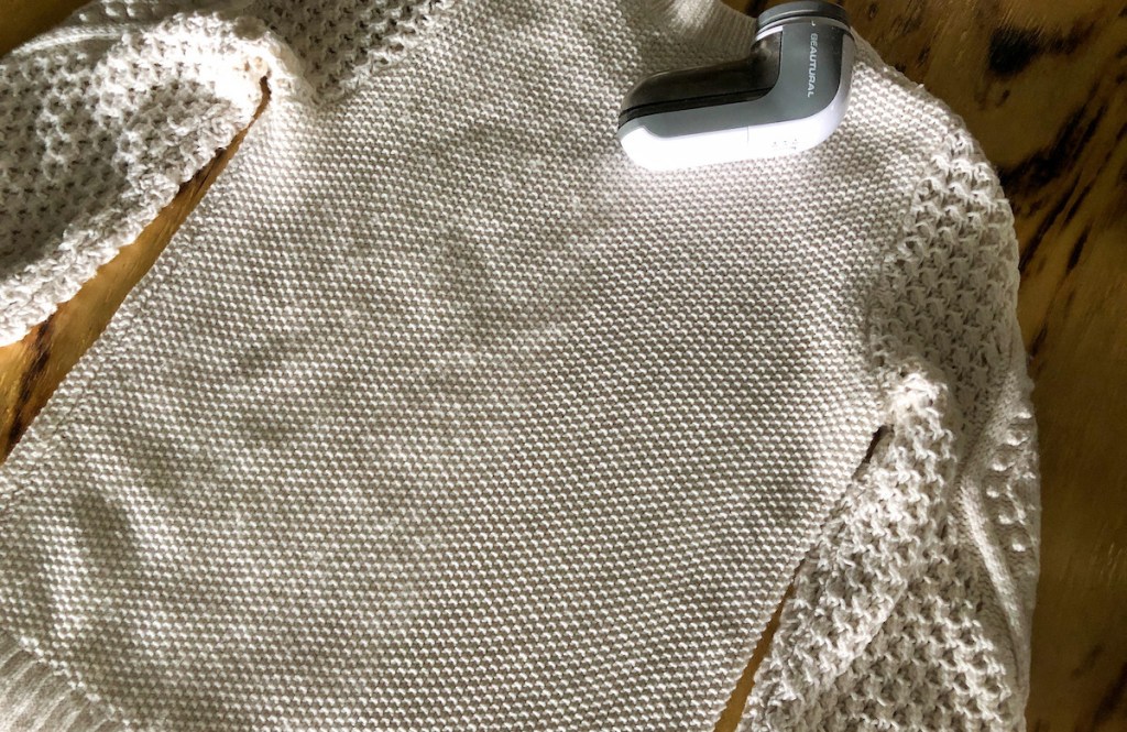 cream sweater laying flat on table with fabric shaver