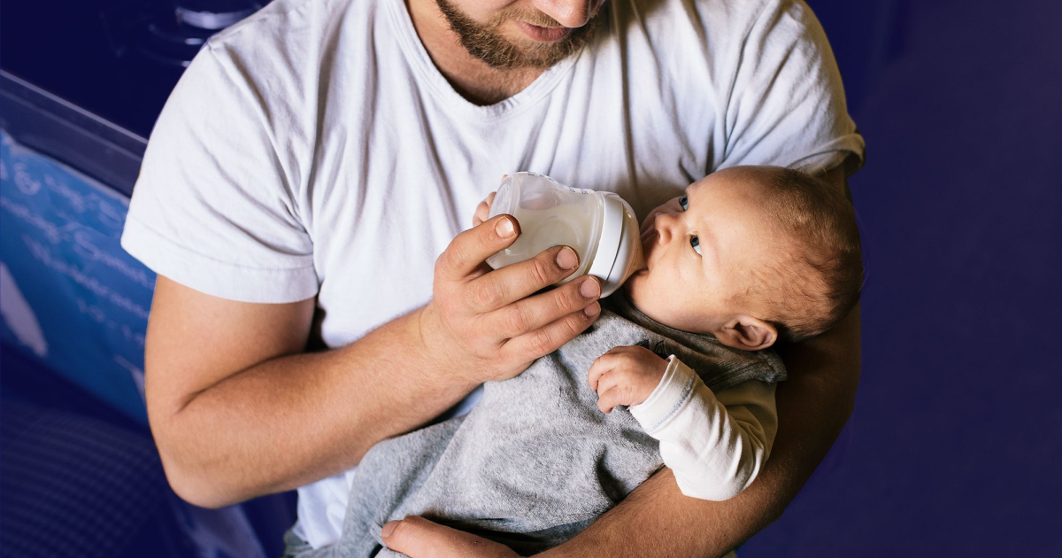 man holding a baby feeding him a bottle