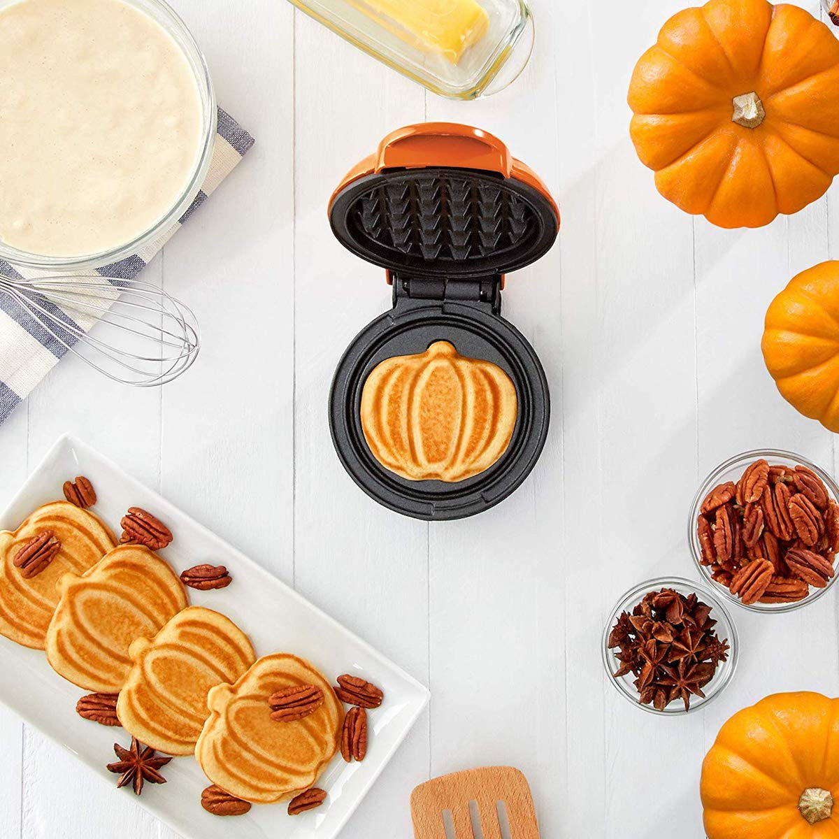 DASH waffle maker in kitchen with bowl of batter and pumpkin shaped waffles
