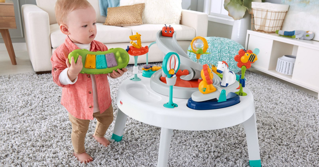 baby standing next to fisher price table