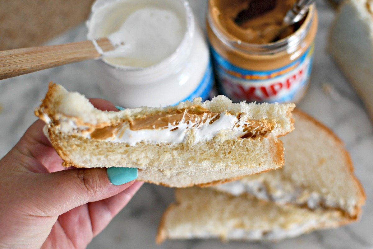 holding a peanut butter and marshmallow fluff sandwich