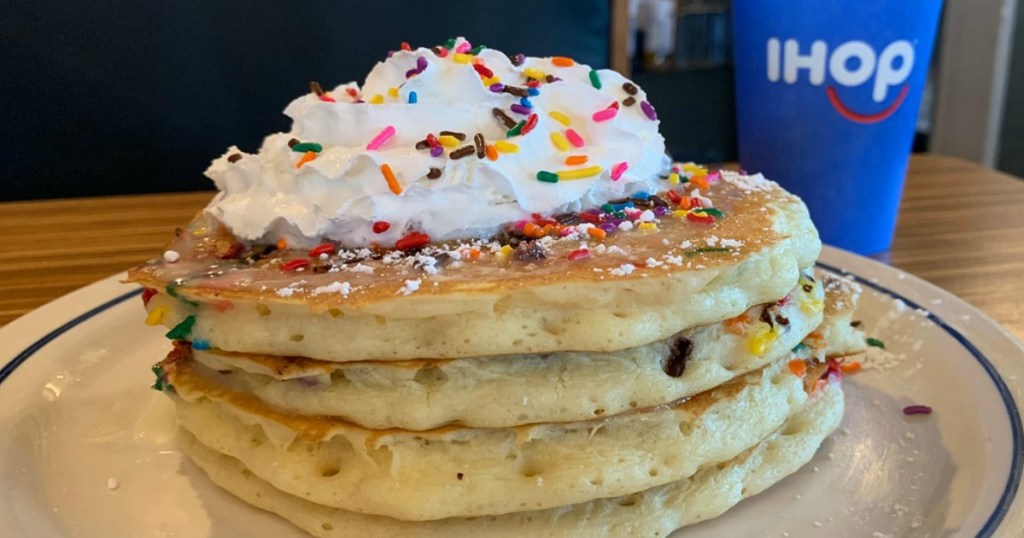 stack of pancakes with whip cream, sprinkles and coffee