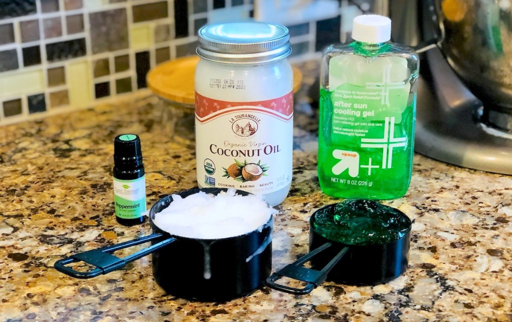 Coconut oil aloe vera gel and peppermint essential oil measuring cups sitting on granite countertop
