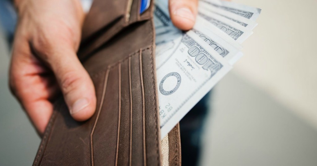 man putting money in a brown wallet