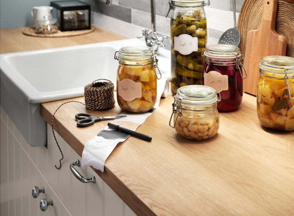 oak countertop with jars of preserved food and farmhouse sink