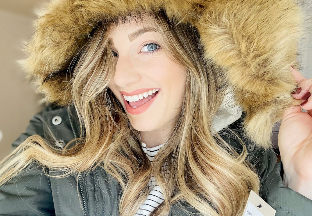 woman smiling wearing fur coat on head