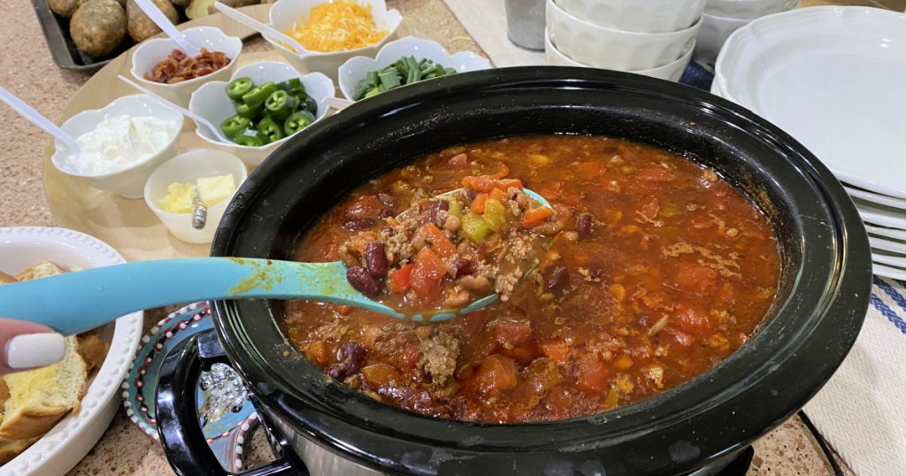 A slow cooker with homemade chili and lots of toppings 