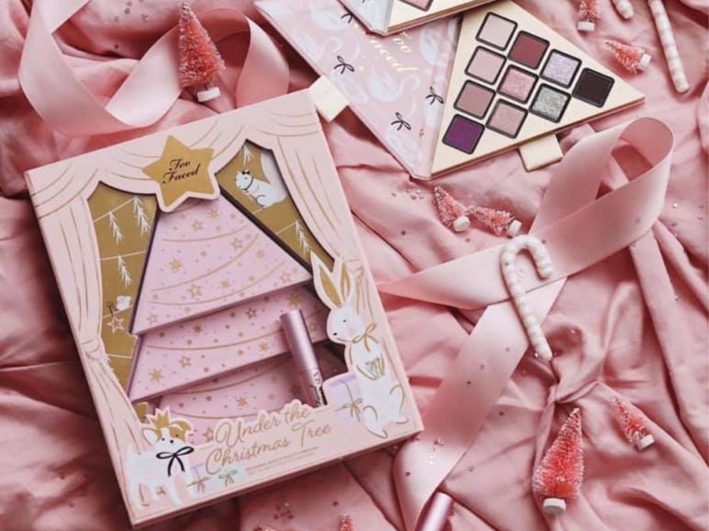 too faced Under The Christmas Tree Set Only $22 (regularly $49) Includes 3 individual palettes with 18 eye shadows, bronzer, blue, and highlighter and deluxe Better Than Sex Mascara on pink sheet with pink christmas trees and candy canes